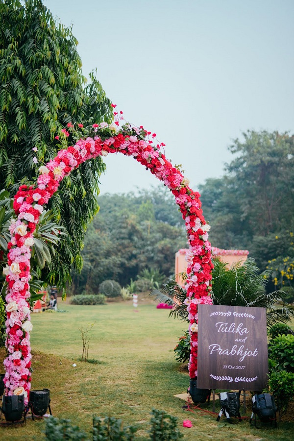 arche de mariage fleurie avec panneau de réception à l'entrée du mariage
